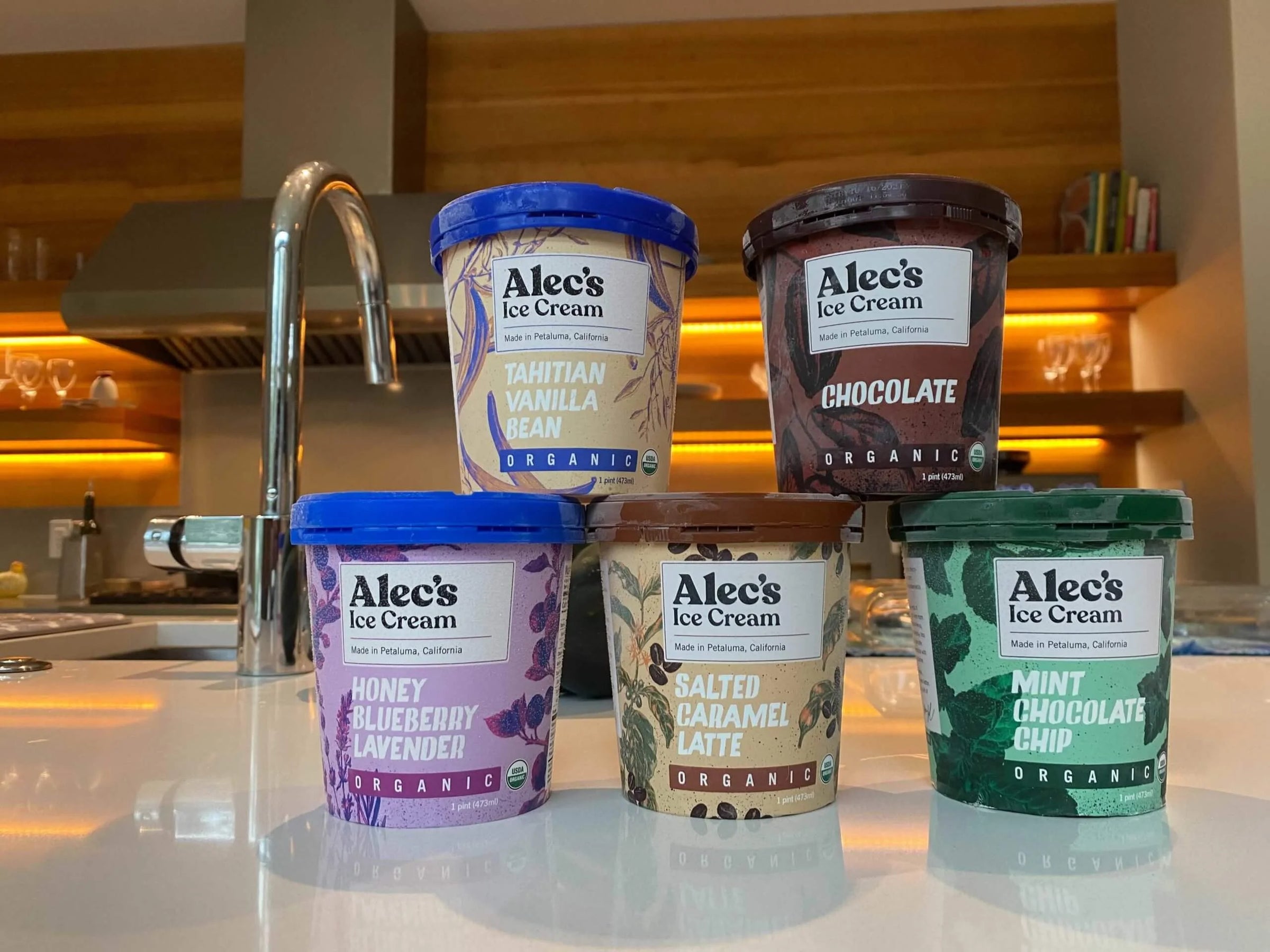 Five containers of Alec's Ice Cream on a kitchen counter with a blurred background.