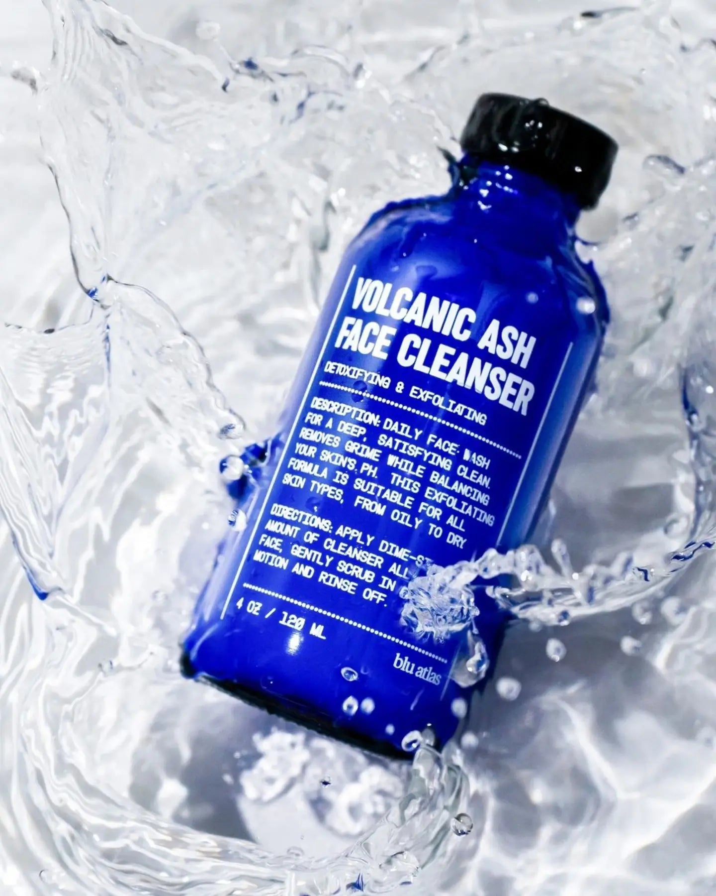 Blue bottle of blu atlas Volcanic Ash Face Cleanser surrounded by water droplets