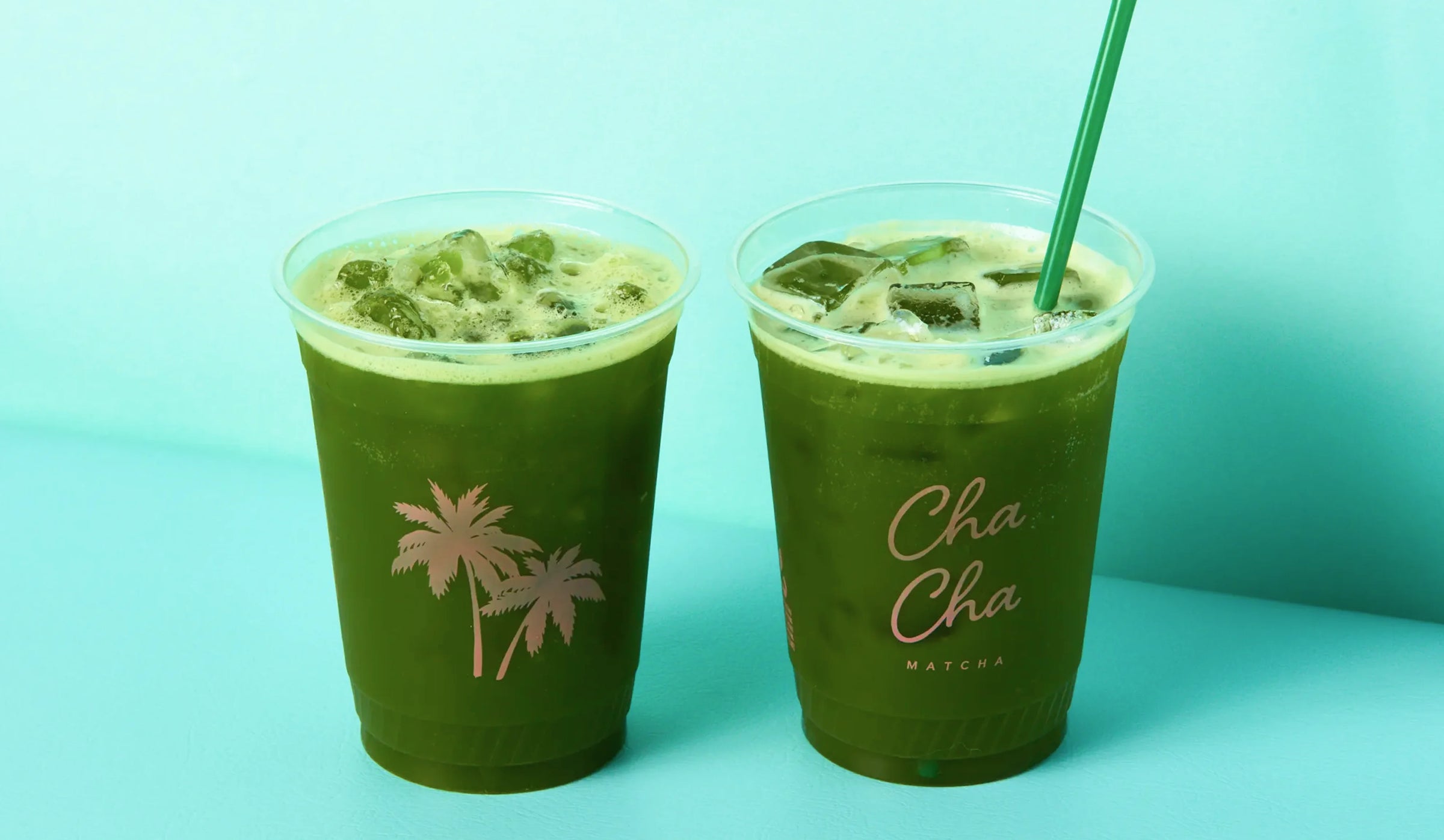 Two green drinks in clear cups with a straw on a teal background