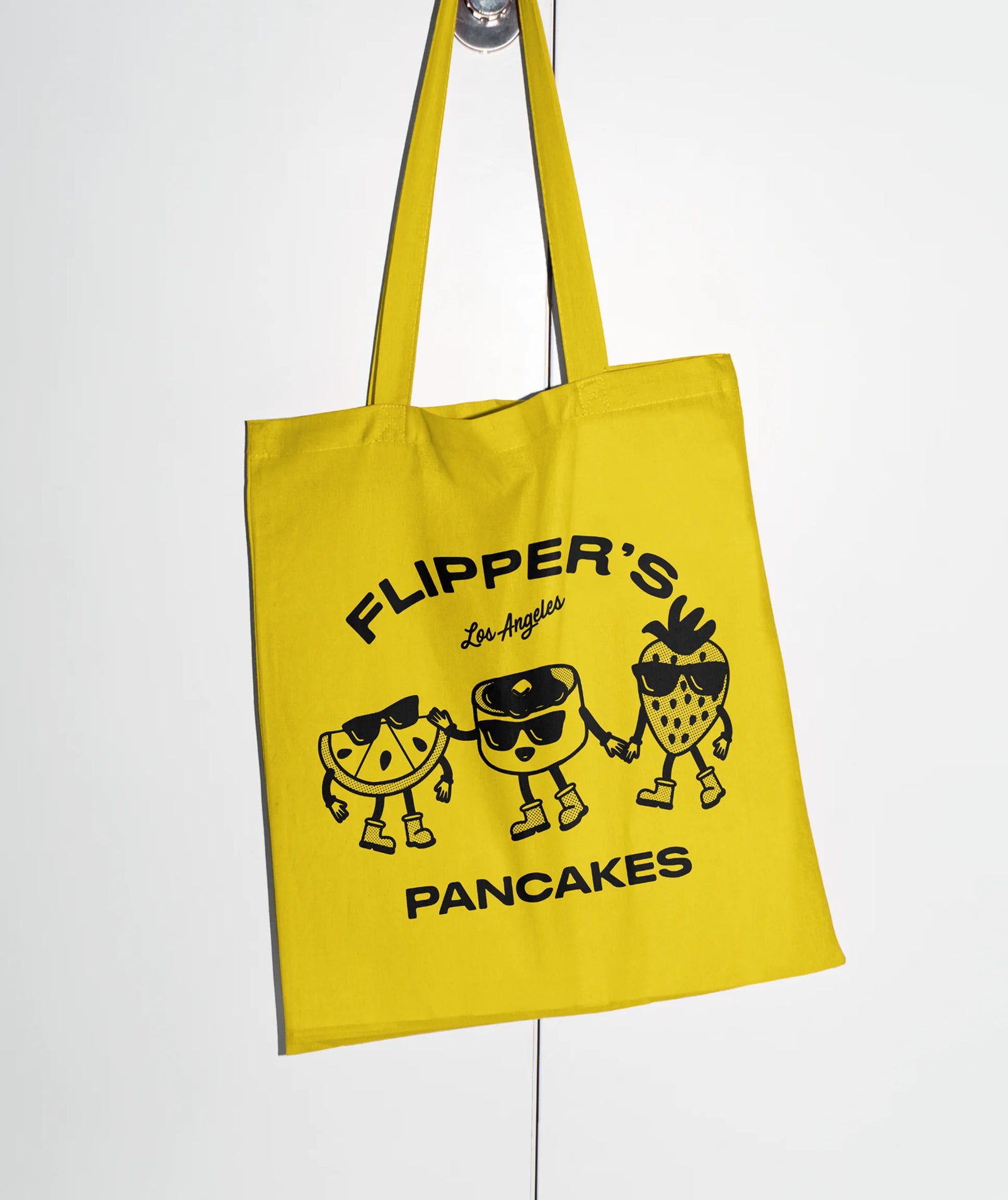 Yellow tote bag with 'Flipper's Pancakes' design on a white background