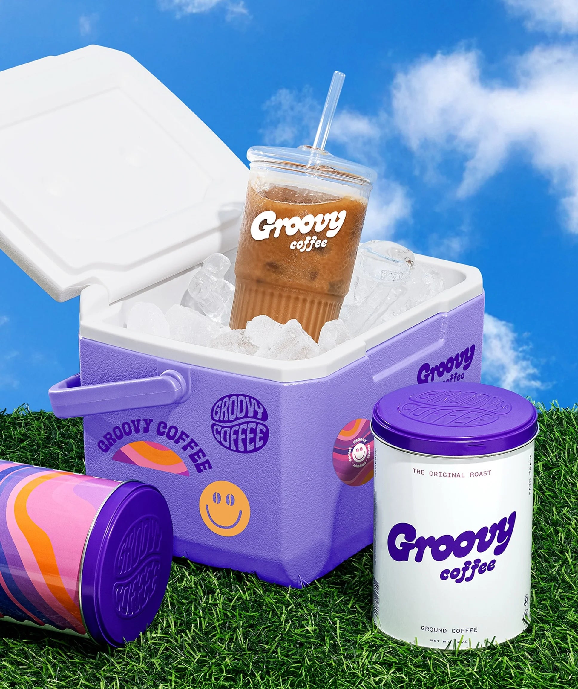 Groovy Coffee products including a cooler, tumbler, and container against a blue sky background.