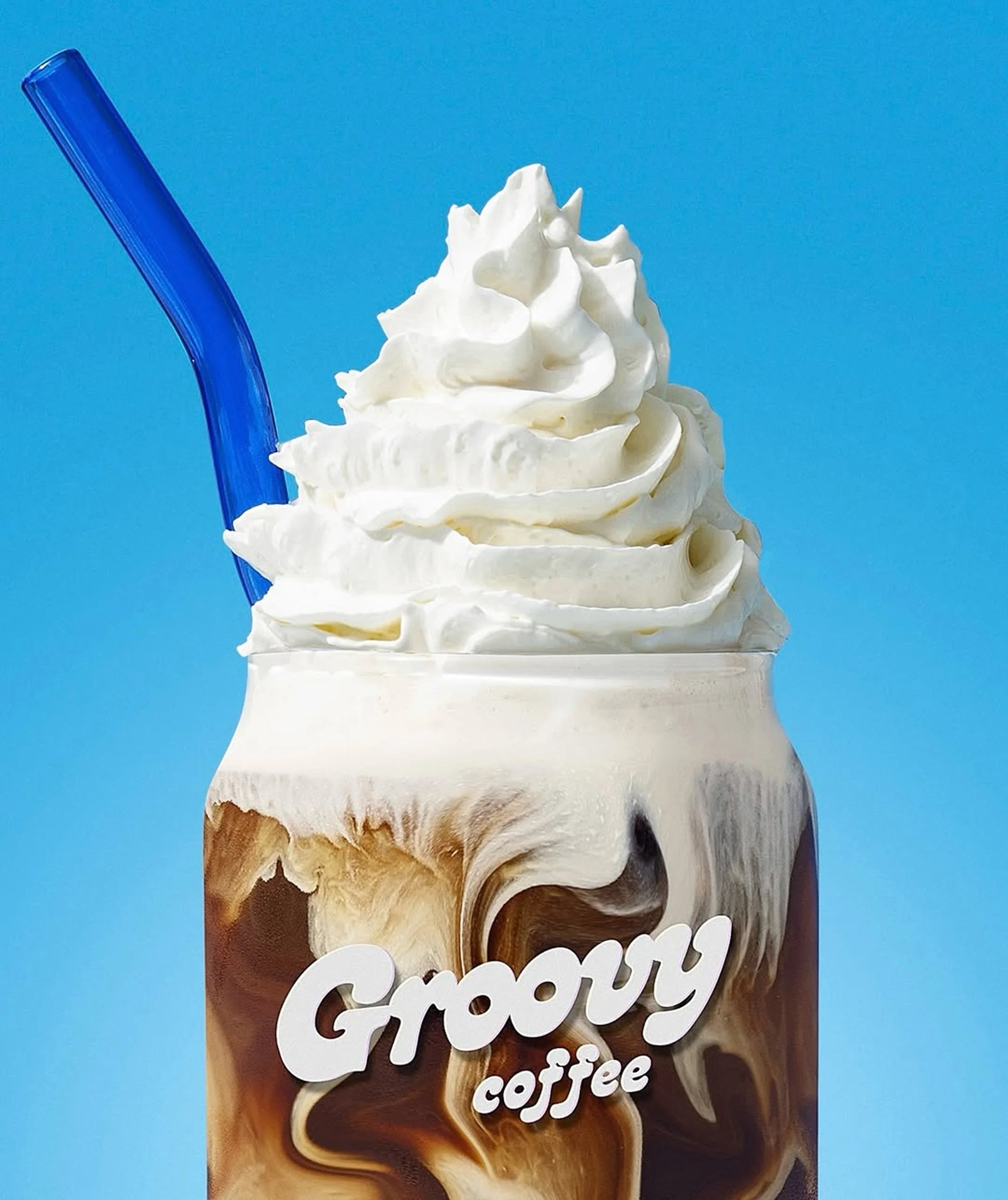 Mocha drink with whipped cream and a blue straw against a blue background, featuring the brand 'Groovy Coffee'.