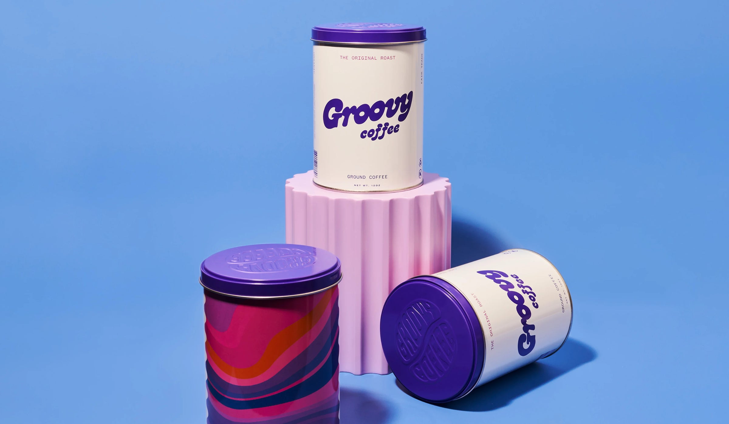 Three 'Groovy Coffee' containers with colorful lids on a blue background