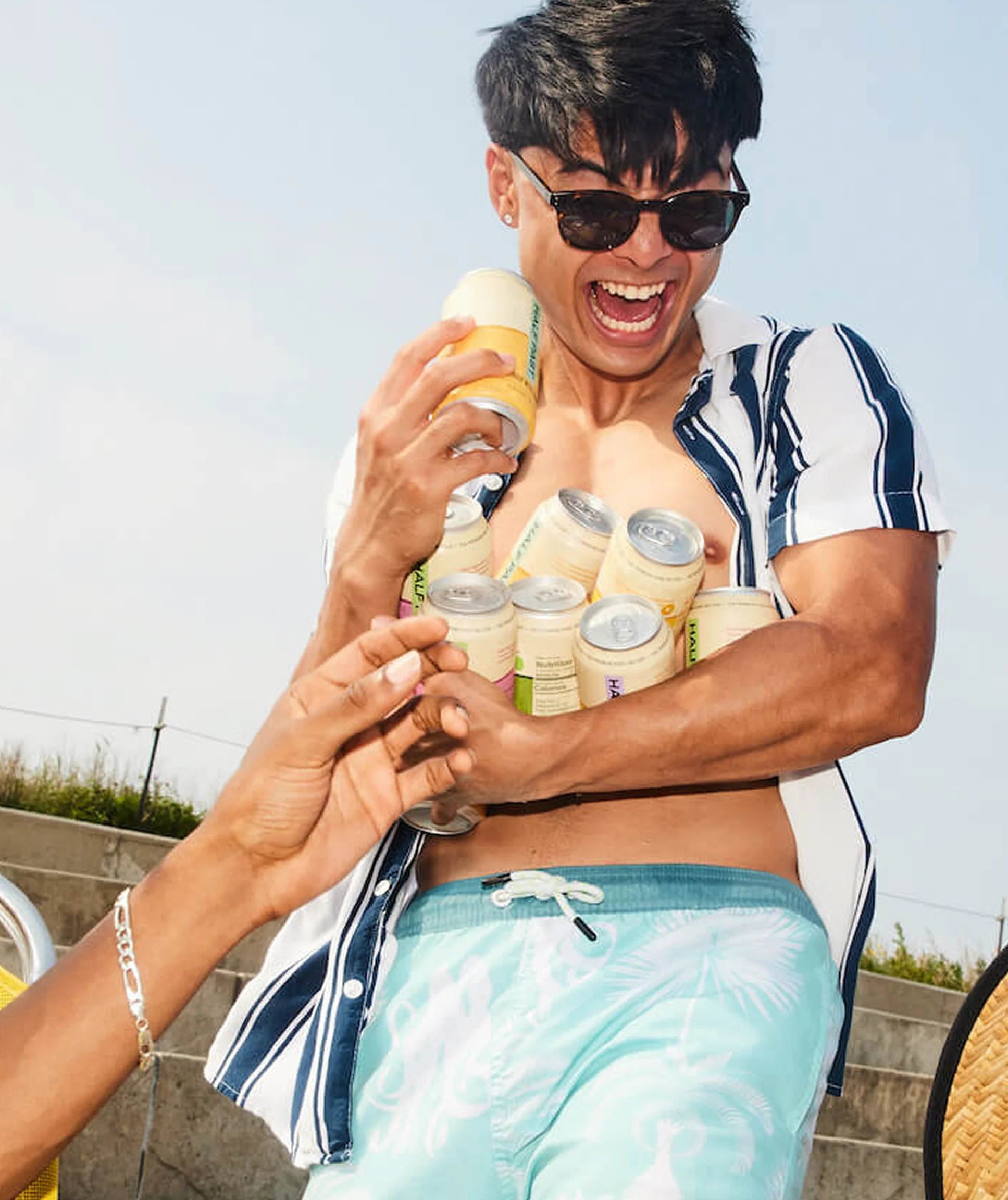 Person holding multiple bottles of a beverage in a casual outdoor setting