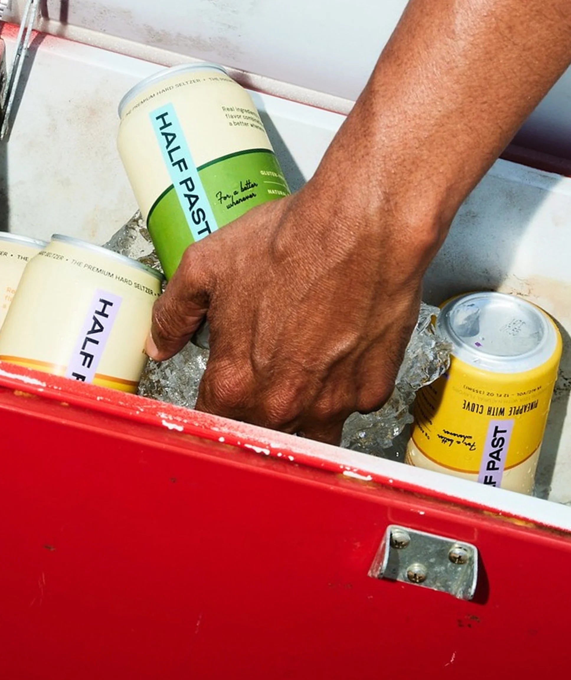 Hand reaching into a cooler with 'Half Fast' energy drink cans.
