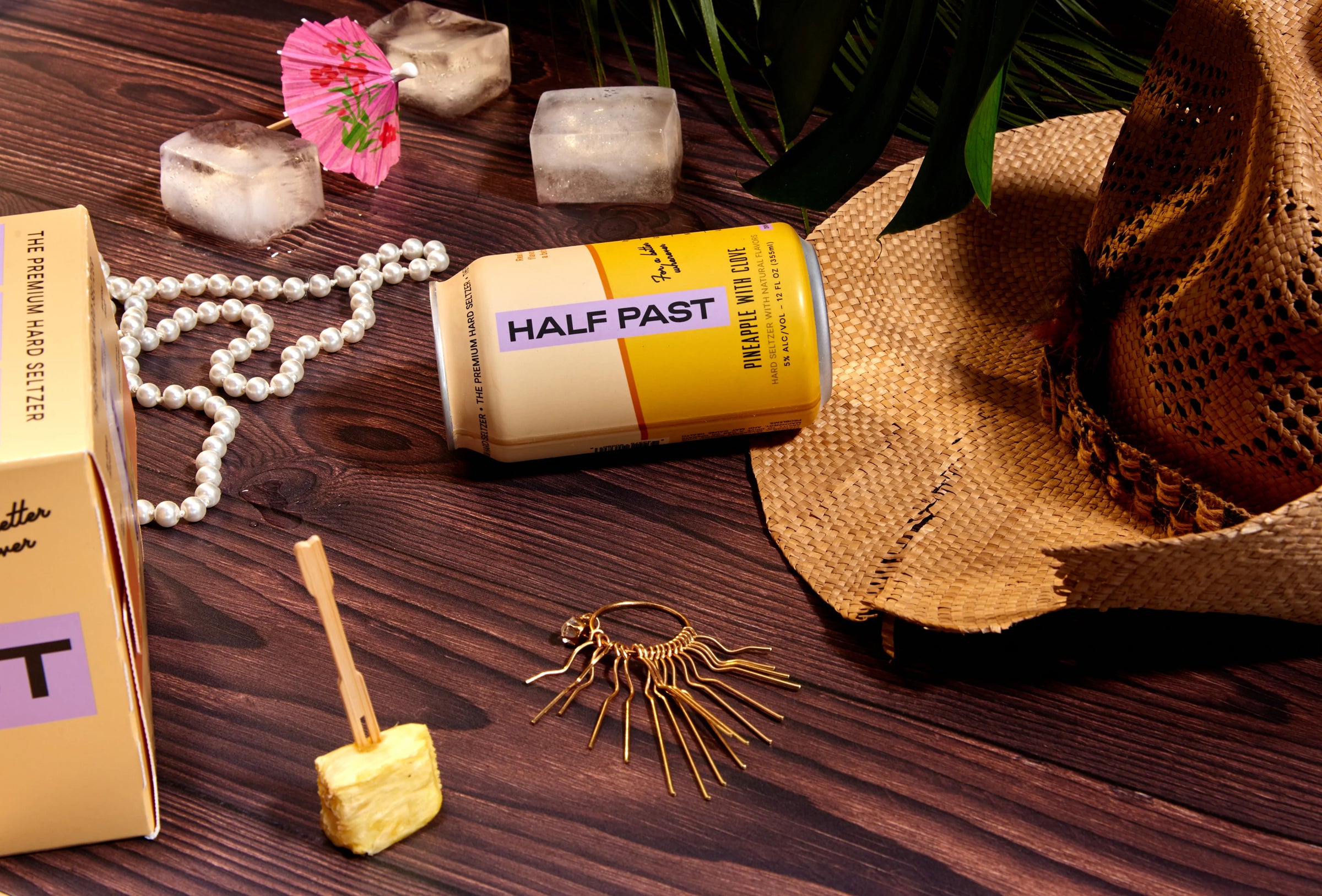 Decorative items including a can labeled 'Half Past', a box, a hat, and jewelry on a wooden surface.