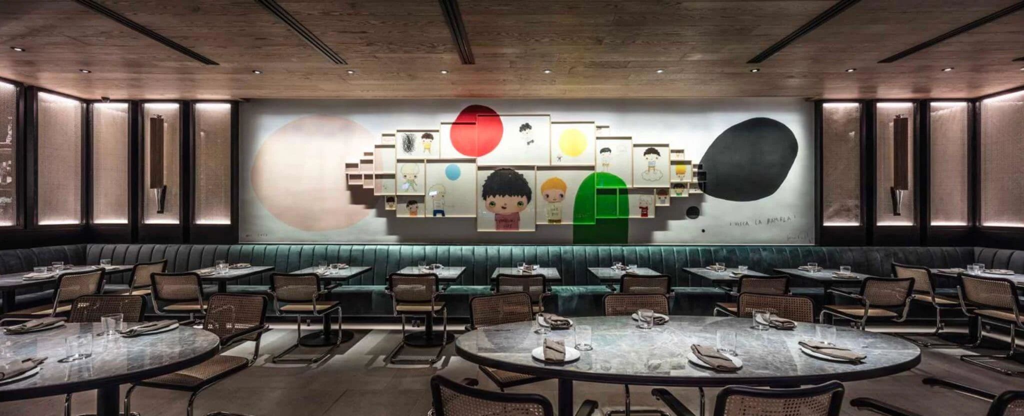 Modern restaurant interior with tables, chairs, and a decorative wall art piece.