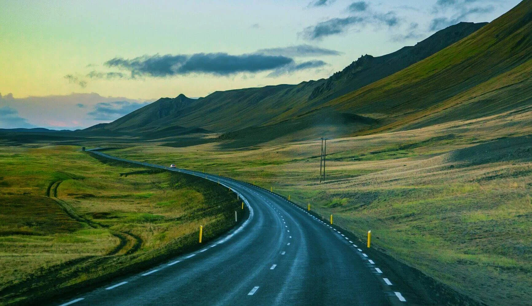 Winding road through a hilly landscape with a blue sky.