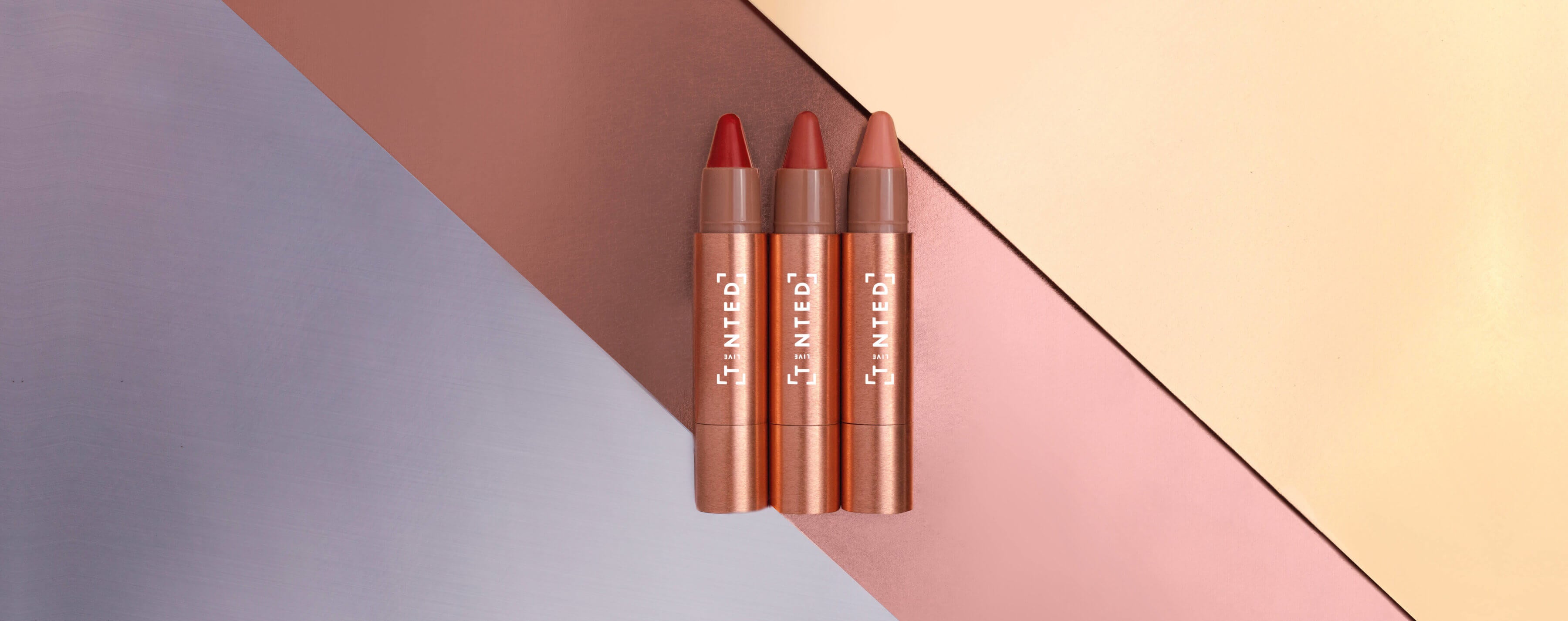 Three lipsticks in red and brown shades on a geometric background