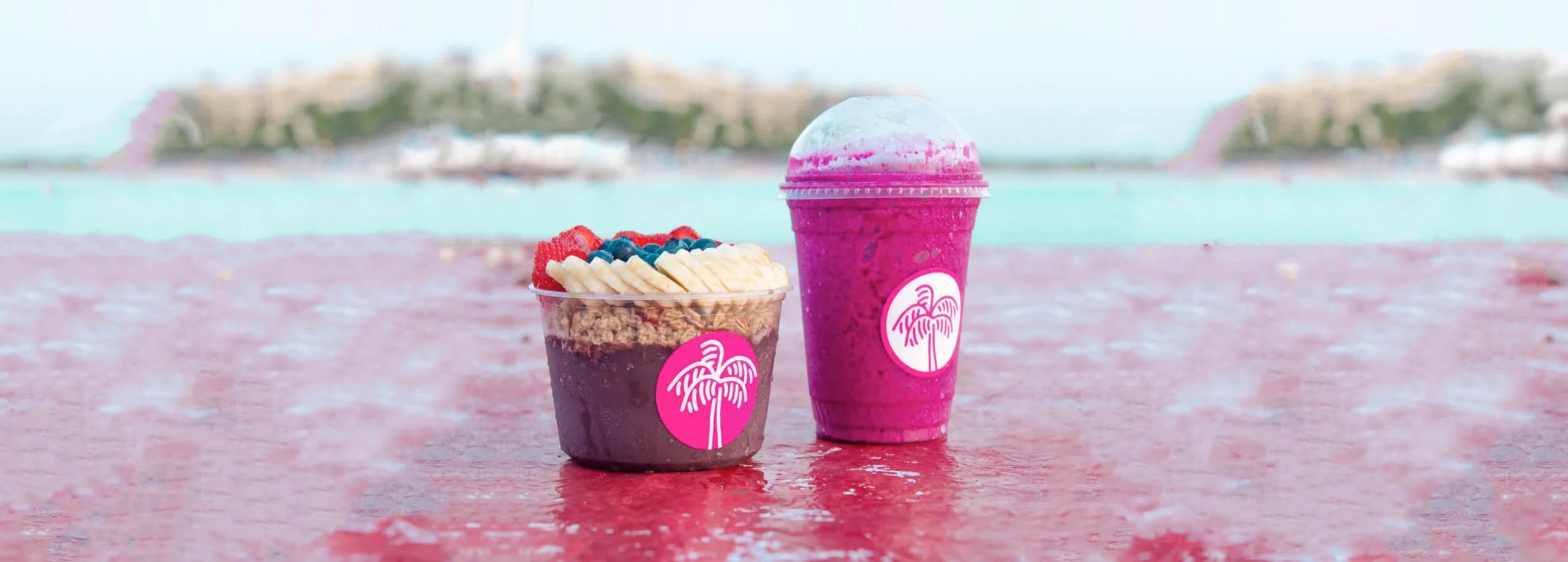Cupcake and pink smoothie with a logo on a red surface with a blurred natural background