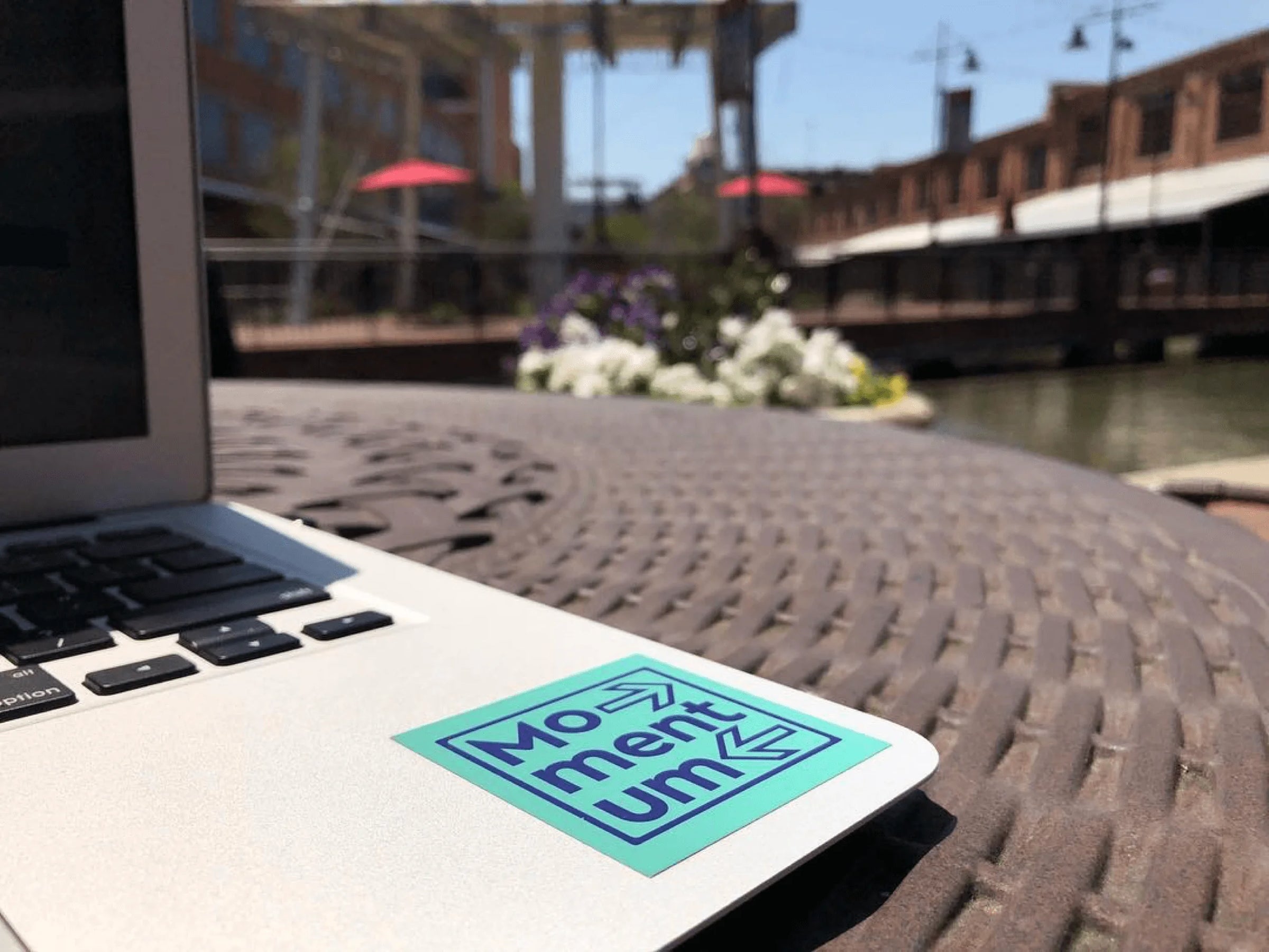 Laptop with a 'Momentum' sticker on a table outdoors with a blurred background