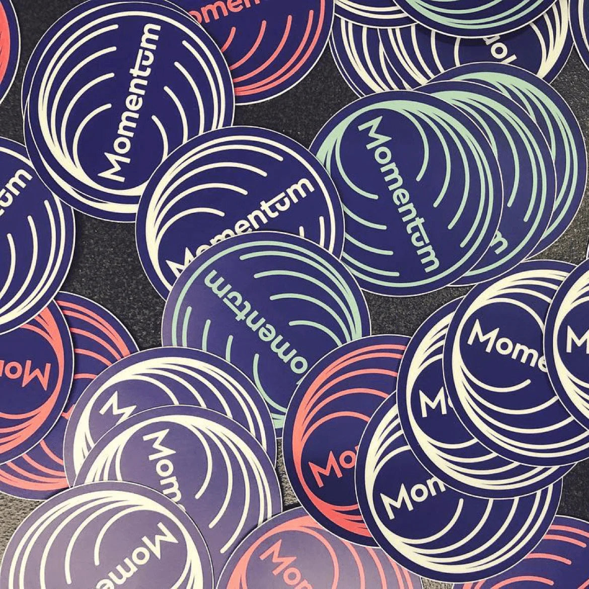 Collection of Momentum brand stickers in various colors on a dark background