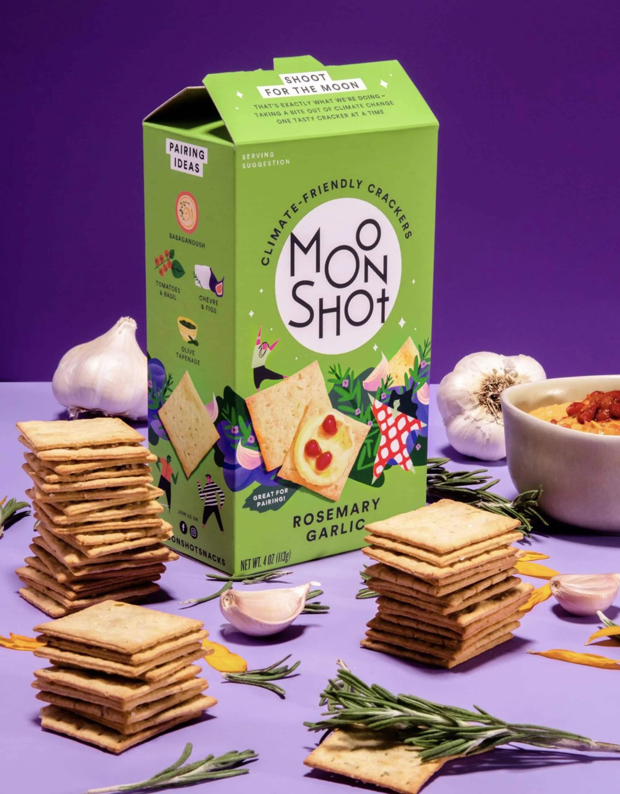 Green box of Moon Shot crackers with crackers and ingredients on a purple background