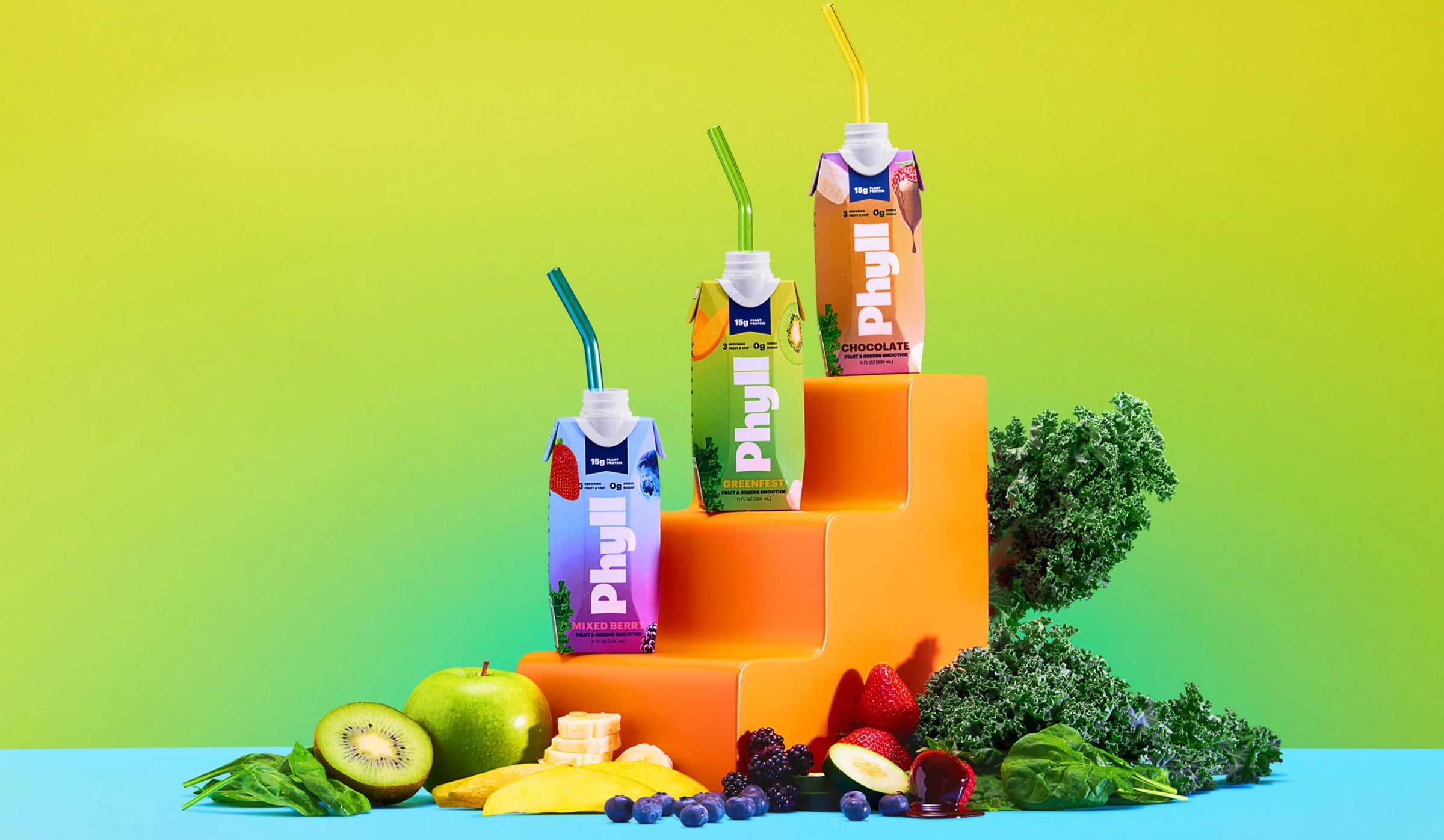 Juice boxes with straws and fresh fruits on a colorful geometric background