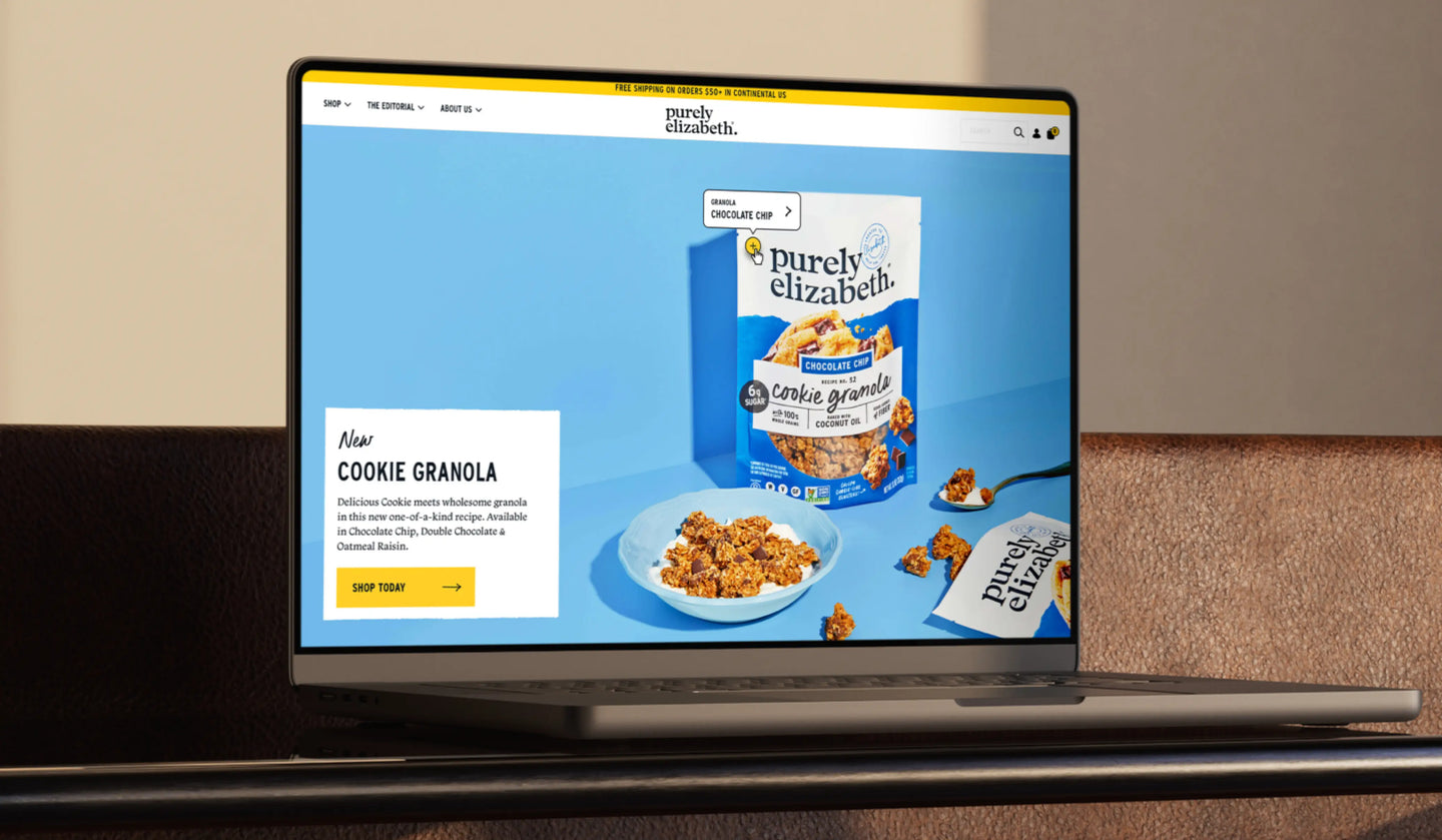 Laptop displaying the Purely Elizabeth website with cookie granola packaging on a blue background.