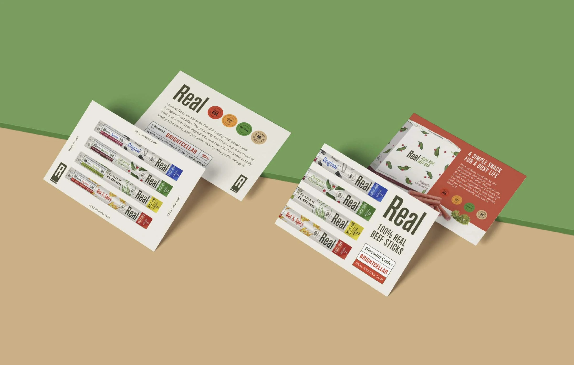 Four packages of Real Snacks beef sticks products on a white background with vegetables.