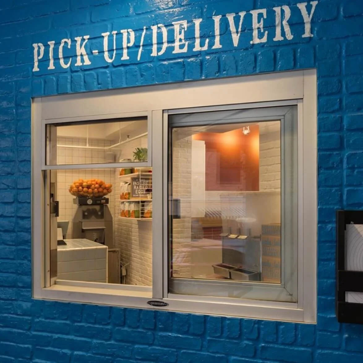 Blue brick wall with a window labeled 'Pick-Up/Delivery' showing an interior view.