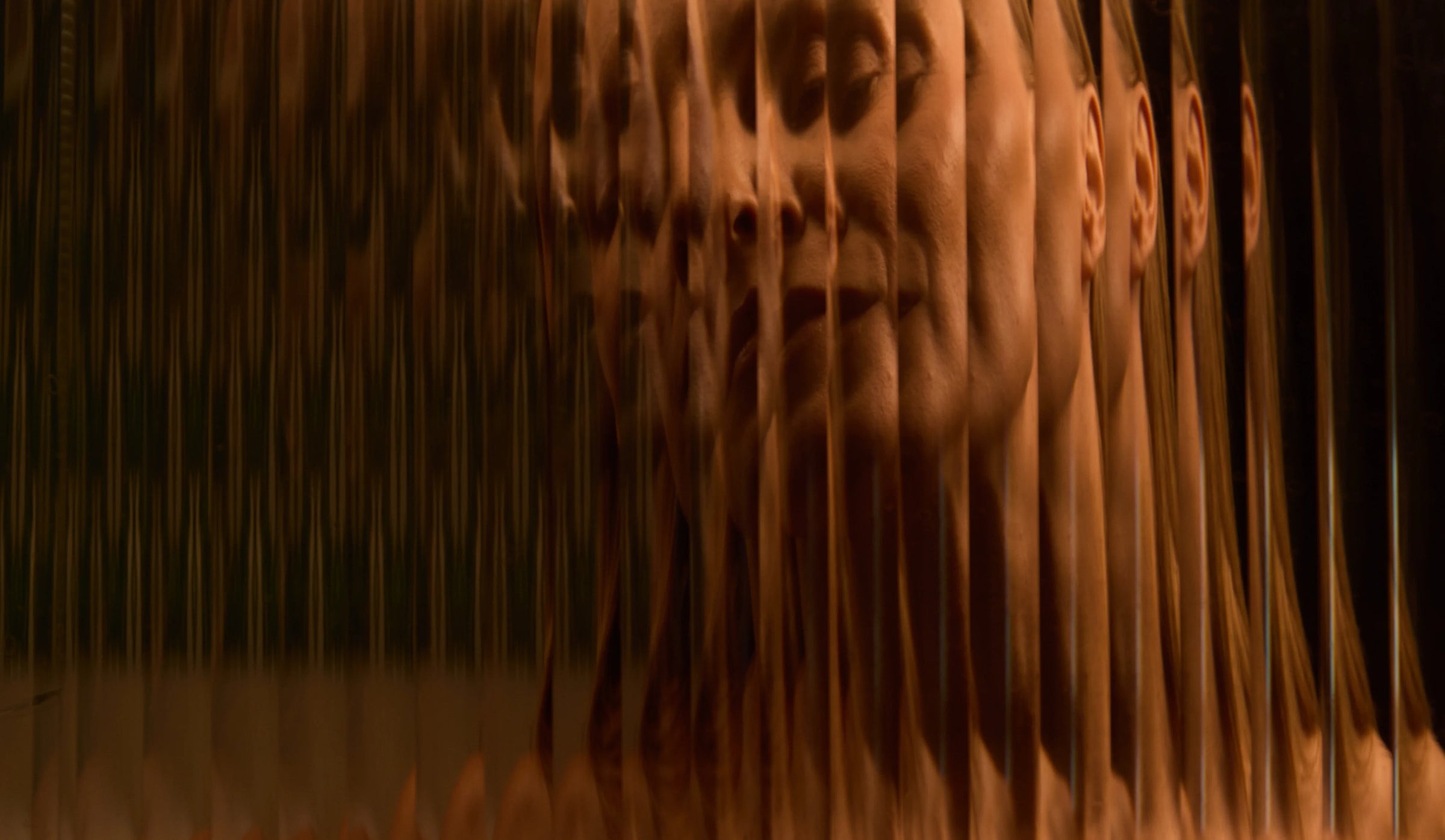 Multiple reflections of a person's face on a textured surface with a warm color tone.